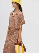 Falda midi marrón con estampado floral en tonos lila, abertura lateral y tiras ajustables.