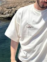 Remera amarilla con estampado en la espalda de una camioneta con una chica y una tabla de surf.