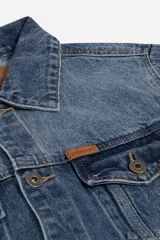 Campera de jean azul de corte clásico con bolsillos laterales y frontales, confeccionada en 100% algodón. Presenta logo en grifa de cuero.