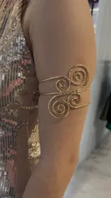 Brazalete dorado para el brazo con diseño de espirales.