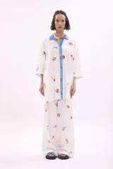 Camisa blanca estampada con dibujos de motivos veraniegos, con cuello clásico y tapeta de botones azul.