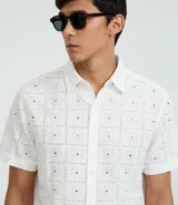 Camisa blanca de algodón con bordado de flores, corte regular, cuello inglés, manga corta y abotonadura frontal.