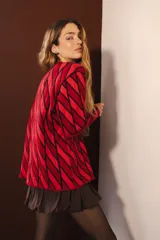 Cárdigan tejido con diseño de rombos rojos y negros, con mangas largas y cierre frontal con botones.