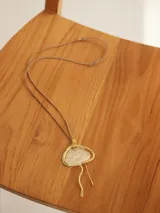 Collar con colgante dorado y plateado en forma de medusa con cordón ajustable.