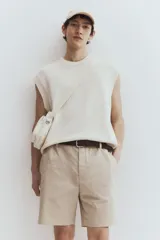 Short color beige de sarga de algodón suave, con elástico en los laterales de la cintura, cierre con botón, bolsillos al bies y bolsillos de atrás ribeteados con botón.