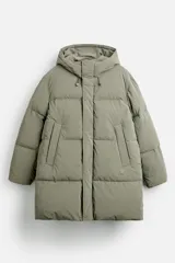 Cazadora acolchada larga color verde oliva, confeccionada en tejido técnico, con cuello alto y capucha ajustable. Tiene mangas largas con puños elásticos, bolsillos laterales y cierre frontal con cremallera oculta y botones a presión.
