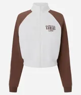 Saco femenino de poliviscosa, color blanco con mangas raglán marrones y ribetes blancos. Tiene cuello alto, cierre frontal de cremallera y bordado lettering "Kansas City" en el pecho.