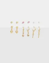 Set de seis pares de aros dorados con diferentes diseños: aros pasantes con forma de corazón, aros con perlas, aros con strass, aros argolla con dije de corazón, aros argolla con dije de strass y aros argolla con dije de llave.
