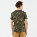 Camiseta de manga corta color verde militar con estampado de hojas de palma en tonos verde claro y negro.