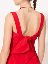 Vestido midi rojo de poplin con lycra, corte evasé, breteles anchos, bolsillos laterales y tajo frontal. Se ajusta en la espalda con un lazo.