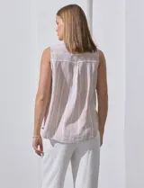 Camisa sin mangas de lino a rayas verticales azules y blancas, con cuello con solapa, escote en V, abertura central con botones y bolsillo en el pecho.