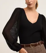 Blusa negra de punto con escote en V y mangas largas abullonadas con detalles de encaje.