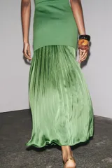 Vestido largo verde con escote redondo y sisas amplias. La parte superior es de punto liso y la falda es plisada de tejido satinado.