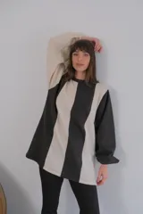 Buzo de mangas largas con diseño de bloques de color en marrón, gris y beige.