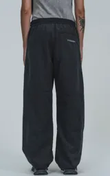 Pantalón negro de corte sastrero holgado, con dos bolsillos laterales, cintura elástica ajustable con tanca y cierre con botón y cremallera.