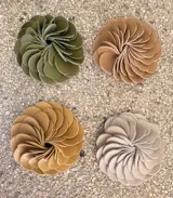 Broche con forma de flor color verde oliva, realizado artesanalmente en Italia con pétalos de cuero superpuestos. Se aplica con imán.