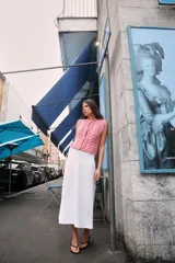 Chaleco tejido de punto color rosado, con cuello redondo y sin mangas. Cierre frontal con botones a presión en forma de flor.