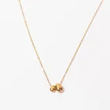 Collar dorado con cadena fina y dije de dos piedras irregulares.