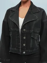 Campera de jean negra con corte cropped, cuello clásico, cierre frontal con botones metálicos y bolsillos con solapa en el pecho.