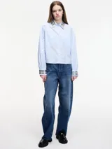 Camisa celeste cropped con tachas en el cuello y puños, con botones en la parte delantera y en los bolsillos. Tiene pinza en la parte trasera.