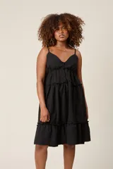 Vestido corto lila con breteles finos, escote en V con botones y falda escalonada con volados.