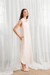 Vestido túnica midi sin mangas, color blanco, con cuello camisero y cierre frontal con botones.