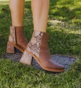 Bota corta de cuero color marrón con detalle de cuero con estampado de piel de serpiente en el talón y taco de madera forrado en cuero.