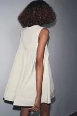 Vestido corto color crema con escote en V y sisas anchas. Tiene forro interior combinado a tono.