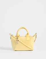 Cartera amarilla con doble asa corta de mano y correa regulable desmontable. Incluye charm colgante de perlas y cierre superior.