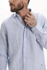 Camisa de algodón color azul claro, con corte regular y botones frontales.