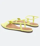 Sandalia plana color amarillo, con punta fina y tira delgada sobre los dedos.