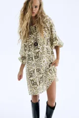 Vestido corto con estampado tipo paisley en tonos beige, verde oliva y negro. Presenta escote redondo con frunce elástico, mangas globo largas con puños elásticos y un lazo fino ajustable a la cintura.