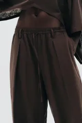 Pantalón blanco de lino, de corte ancho y tiro medio, con cintura elástica ajustable con cordones y bolsillos laterales.