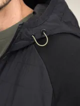 Campera negra con capucha, cierre frontal y bolsillos laterales con cierre.