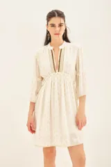 Vestido corto color blanco con estampado de lunares dorados, escote en V con detalle de bordado y mangas al codo con volantes.