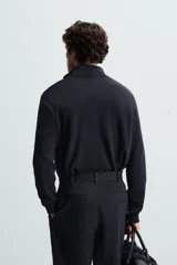 Jersey negro de punto con cuello perkins y cierre frontal de cremallera.