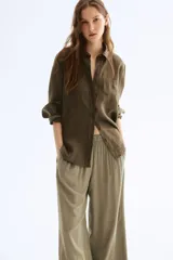 Pantalón tobillero color verde oliva de viscosa con caída suave, tiro alto con elástico en la cintura, bolsillos laterales y piernas amplias rectas.