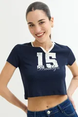 Remera corta color crema con cuello redondo y ribete azul marino. Estampado frontal con la inscripción "Manhattan New York City" en azul.