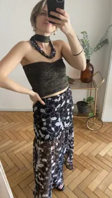 Falda larga de tela estampada con motivos florales en tonos marrones, negros y violetas. Tiene elástico en la cintura y corte acampanado.