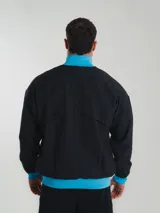Campera deportiva negra con detalles celestes, cierre frontal y cuello alto. Logo de Nike bordado en el pecho y escudo de Uruguay en el brazo.