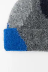 Gorro tipo beanie tejido con alpaca, con diseño de bloques de color en gris, azul y azul marino.