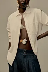 Camisa color crema de hilatura con algodón y lyocell, con cuello solapa, manga larga acabada en puño y bolsillo de plastrón en el delantero.