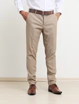 Traje de vestir color tostado, compuesto por saco con solapa de muesca, cierre de dos botones, bolsillos con solapa y pantalón de corte recto.