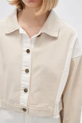 Campera corta de algodón color beige con detalles en blanco, de manga larga y cierre frontal con botones.