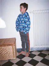 Pantalón de jean celeste con efecto lavado, corte recto y largo a la rodilla. Presenta una cinta vertical color violeta en la pierna izquierda, una cinta vertical color verde en la pierna derecha y una cinta horizontal color rosa en la parte inferior de ambas piernas.