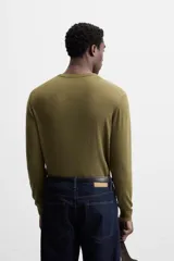 Jersey negro de lana con acabado mercerizado, corte relaxed fit, cuello redondo y manga larga con terminaciones en rib.