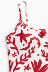 Traje de baño enterizo blanco con estampado de motivos marinos en color rojo.