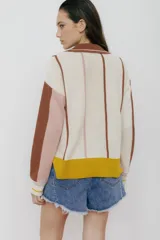 Sweater de punto color verde esmeralda, con cuello polo, mangas largas color crema y detalles en rosa.