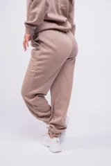 Pantalón de jogging color beige con cintura elástica y logo estampado en blanco en el muslo.