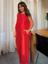 Pantalón de lino rojo de corte recto con botones decorativos en el ruedo.